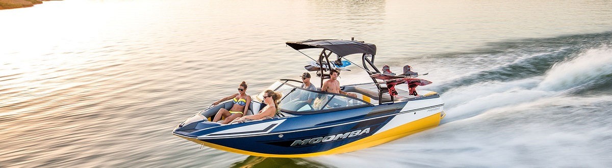 Group of four people speeding through the water on a Moomba boat